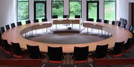 Byrådssal Mariagerfjord Kommune med stort ovalt bord med stole omkring